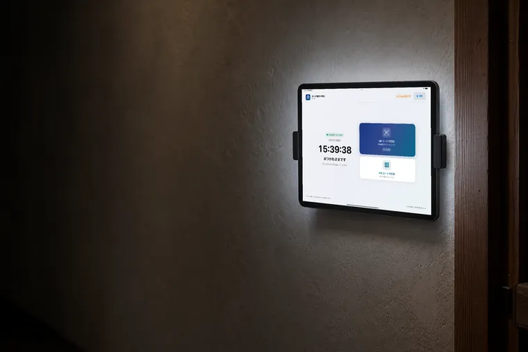 壁に取り付けられ、打刻ぽんの待受画面を表示しているiPad